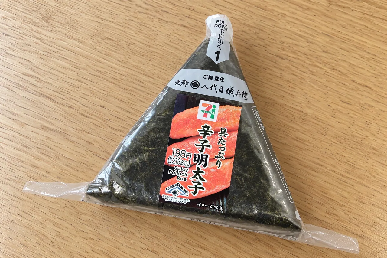 公式の商品画像を基に、形と具の量を保って食卓の背景を編集した手巻おにぎり 具たっぷり辛子明太子の生成画像