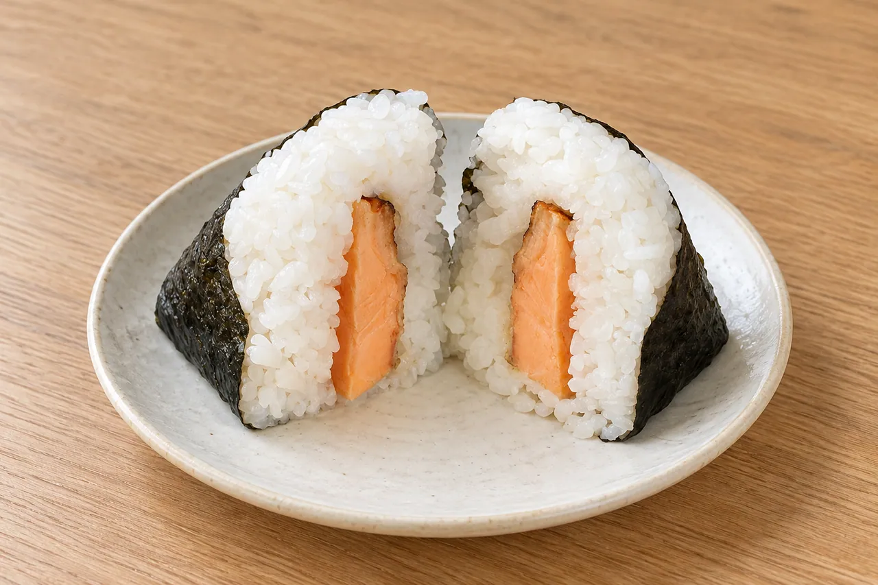 公式の商品画像を基に、形と具の量を保って食卓の背景を編集したごちむすび 鮭はらみの生成画像
